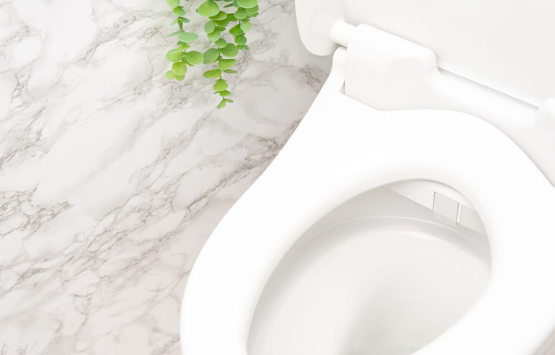 モダンなバスルームに白い大理石の壁と白いトイレがある。