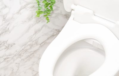 モダンなバスルームに白い大理石の壁と白いトイレがある。