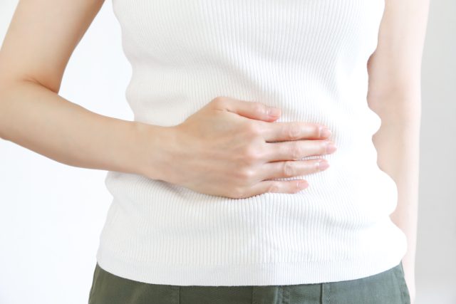 若い女性がお腹を押さえている。