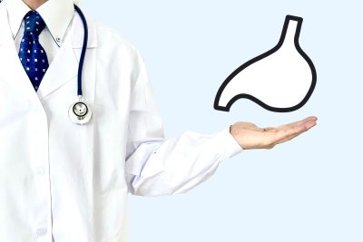 手のひらに胃のイラストを乗せた、聴診器を首にかけた白衣の医師